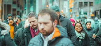 An urban street scene showing diverse people in thoughtful expressions during rush hour.