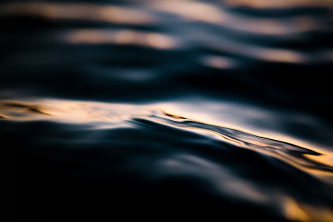 An abstract shot of rippling water reflecting muted colors in the dark.