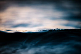 Close-up of ocean waves with light reflections, emphasizing calm and depth.