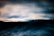 Close-up of a cozy hoodie fabric with ocean waves softly blurred in the background.