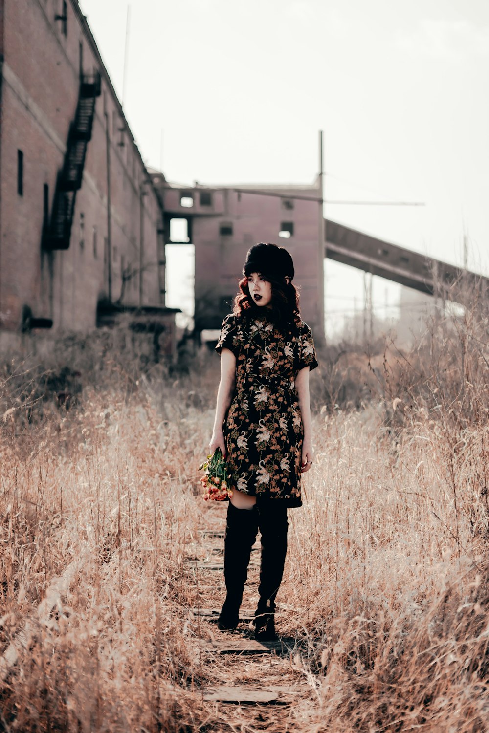 woman in black and white floral dress standing on brown grass field during daytime