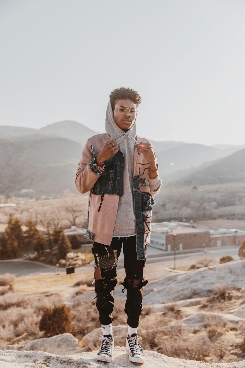 man in brown leather jacket standing on brown field during daytime