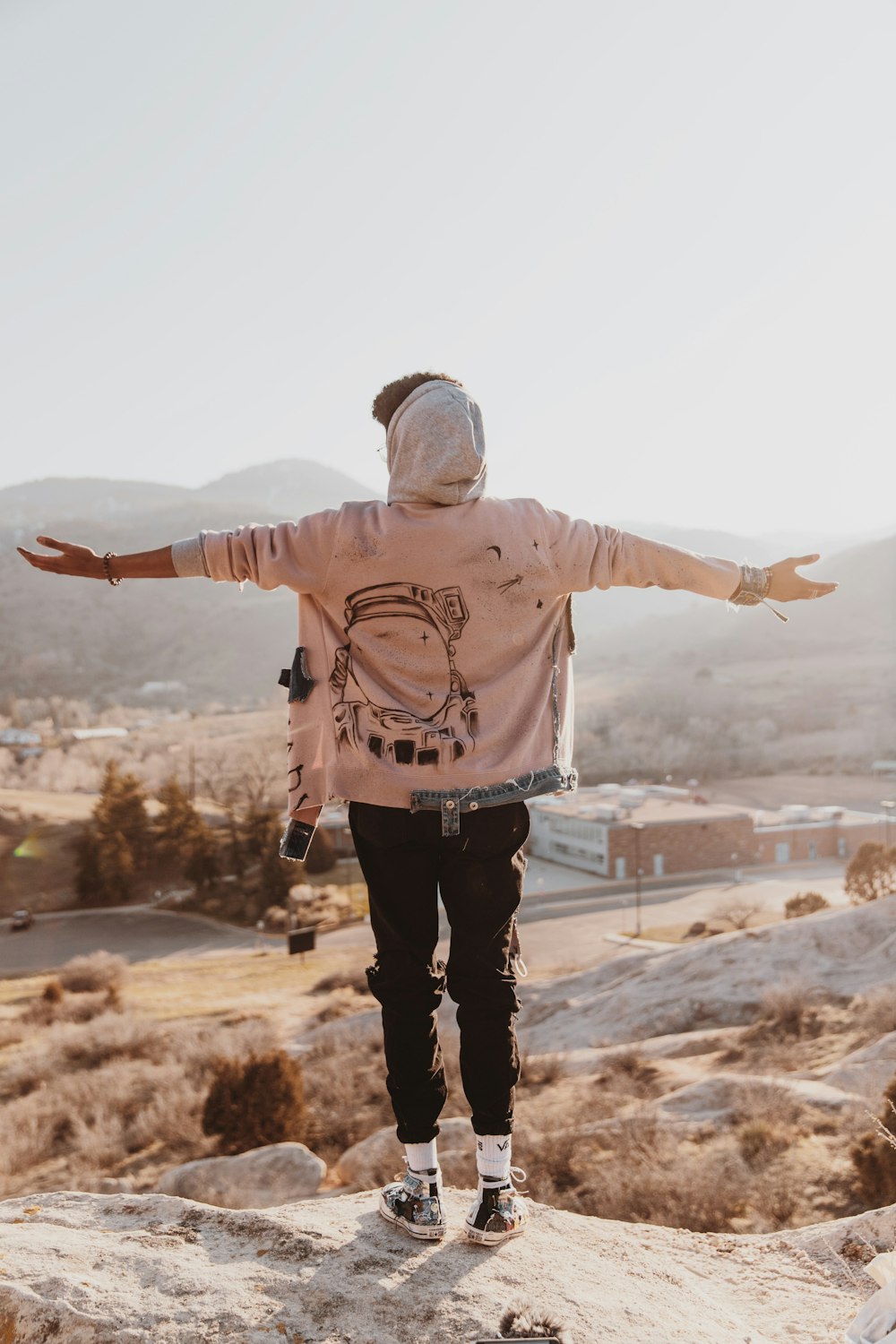 man in pink sweater standing on brown field during daytime