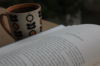 A vibrant mug featuring the eruditomillonario logo sitting beside an open ebook on a minimalist desk.