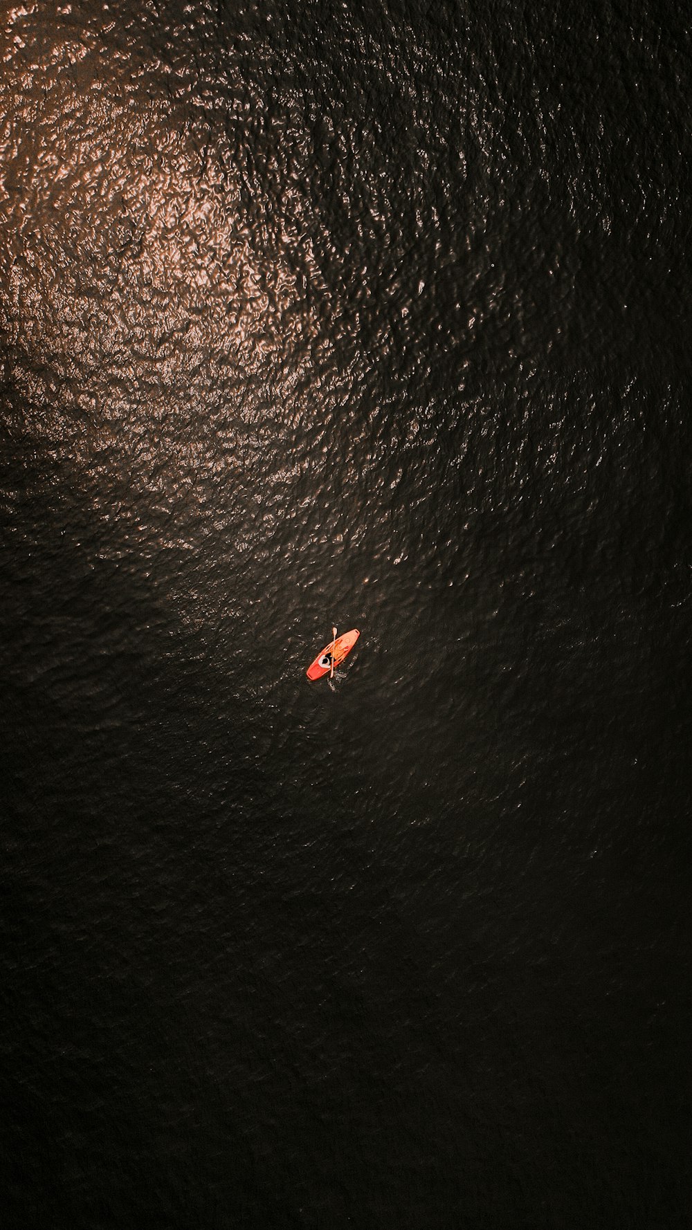 person riding on red kayak on body of water during daytime