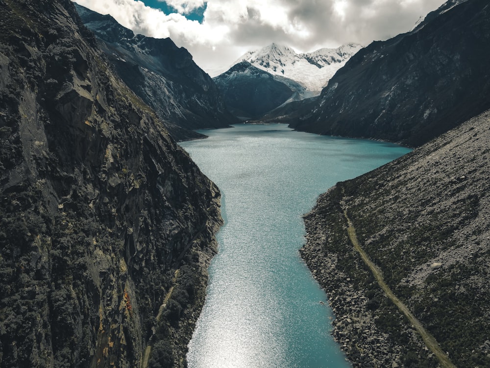 Lago tra le montagne rocciose sotto il cielo blu e le nuvole bianche durante il giorno