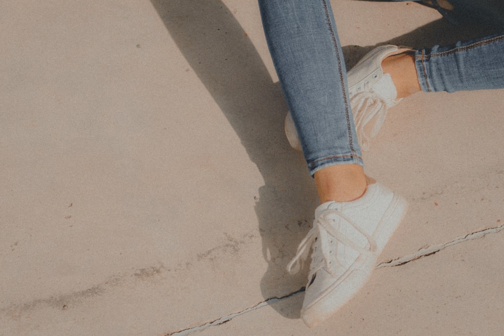 person in blue denim jeans and white nike sneakers