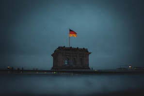 An architectural structure with a large German flag flying on top is prominently displayed. The scene is dimly lit, suggesting an overcast or evening setting.