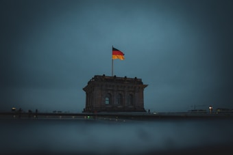 An architectural structure with a large German flag flying on top is prominently displayed. The scene is dimly lit, suggesting an overcast or evening setting.