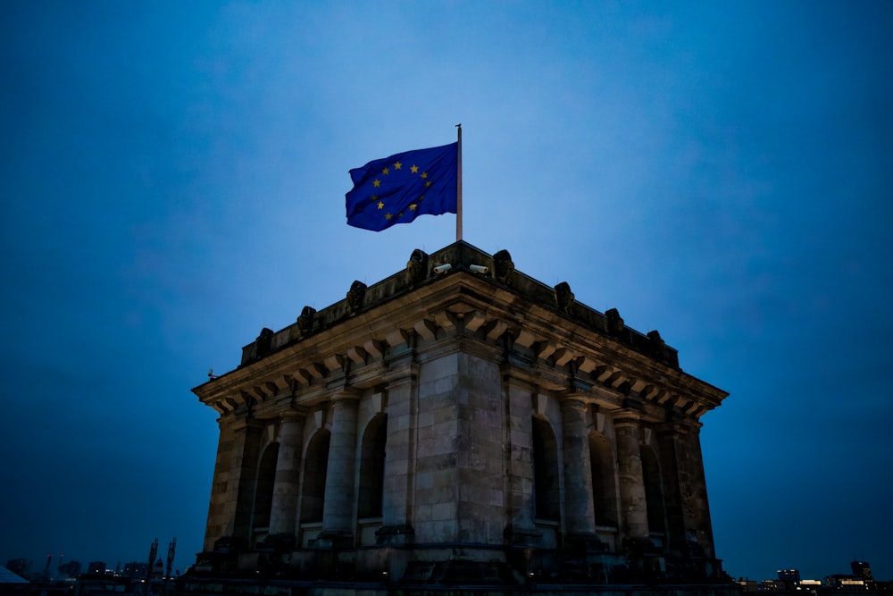 blau-weiße Sternflagge auf dem Dach des braunen Betongebäudes