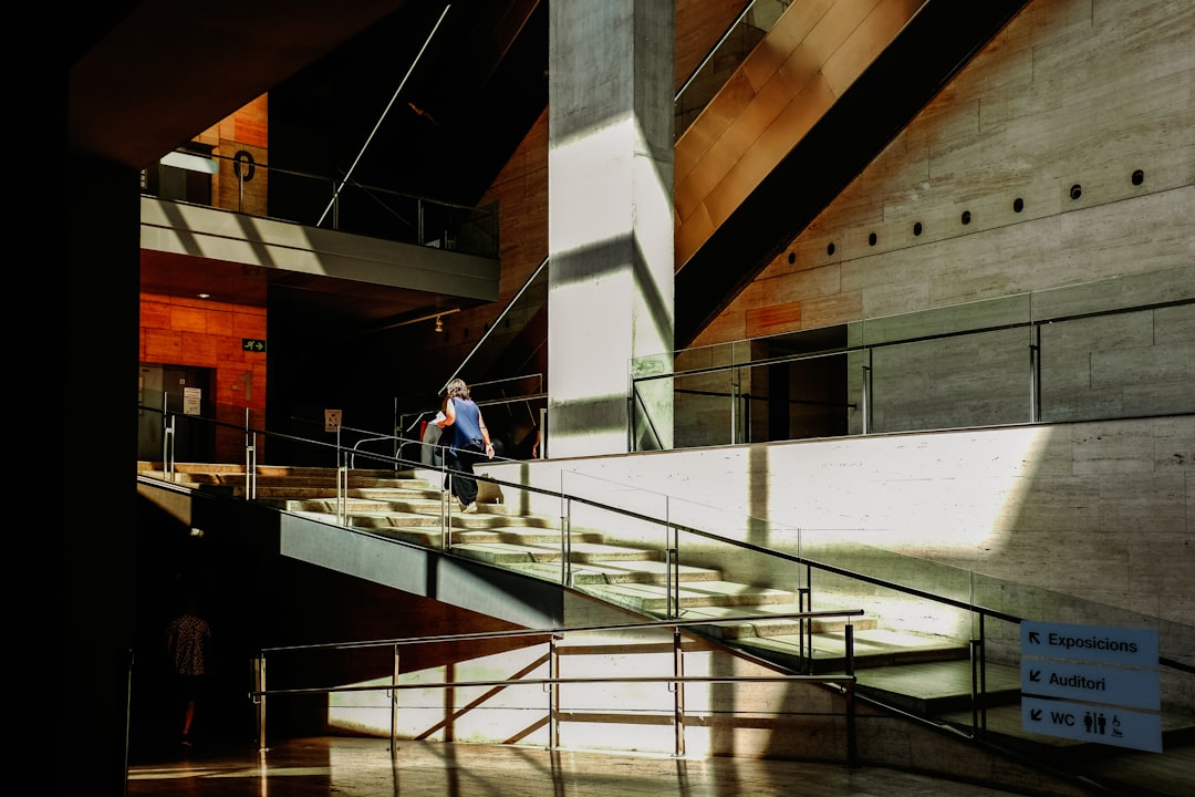 man in blue shirt walking on white concrete staircase