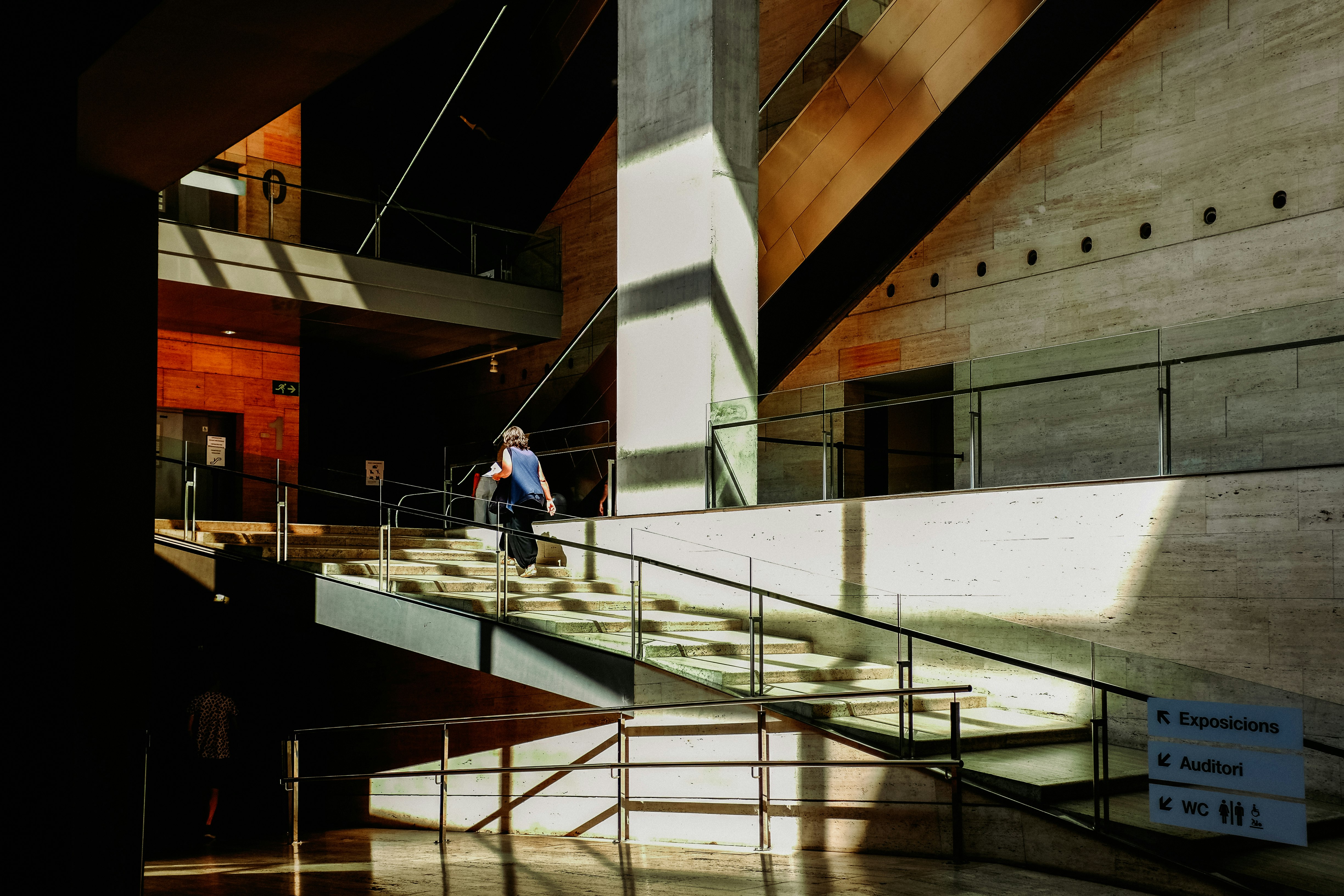 man in blue shirt walking on white concrete staircase