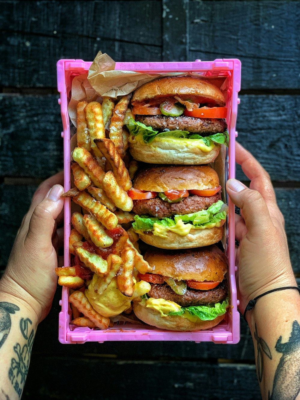person holding burger with cheese and lettuce