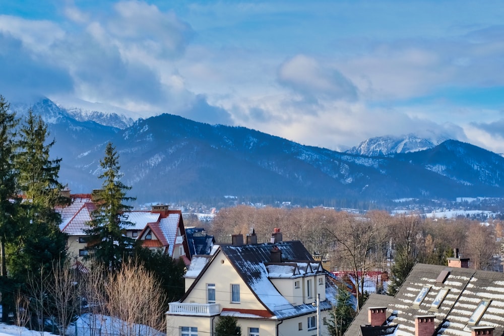 white and brown house near green trees and mountain under blue sky during daytime