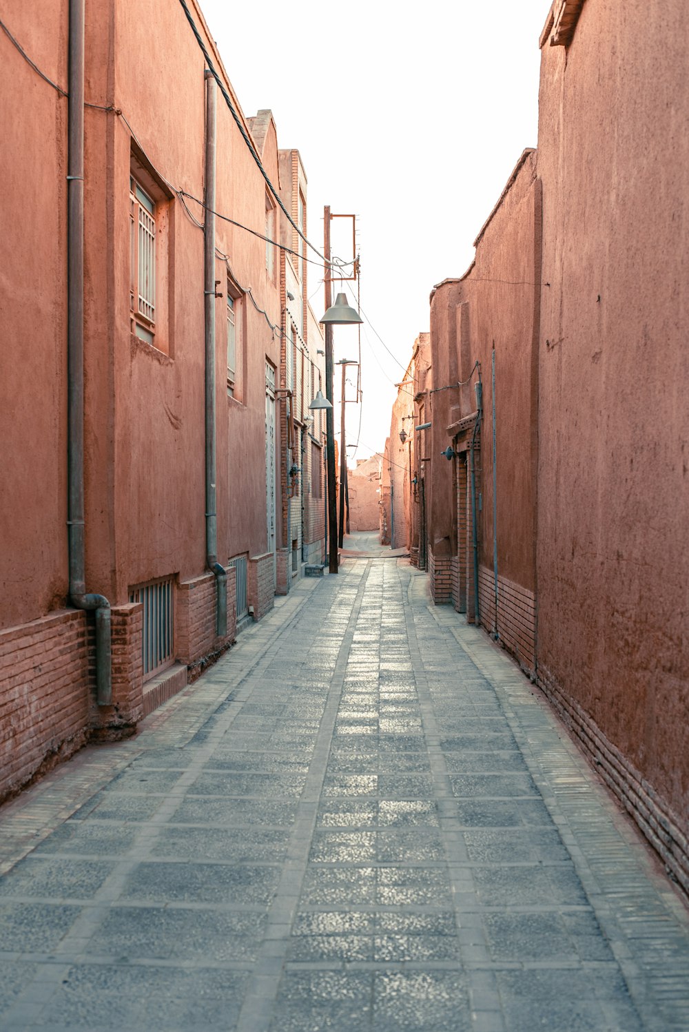 gray concrete pathway between brown brick wall during daytime