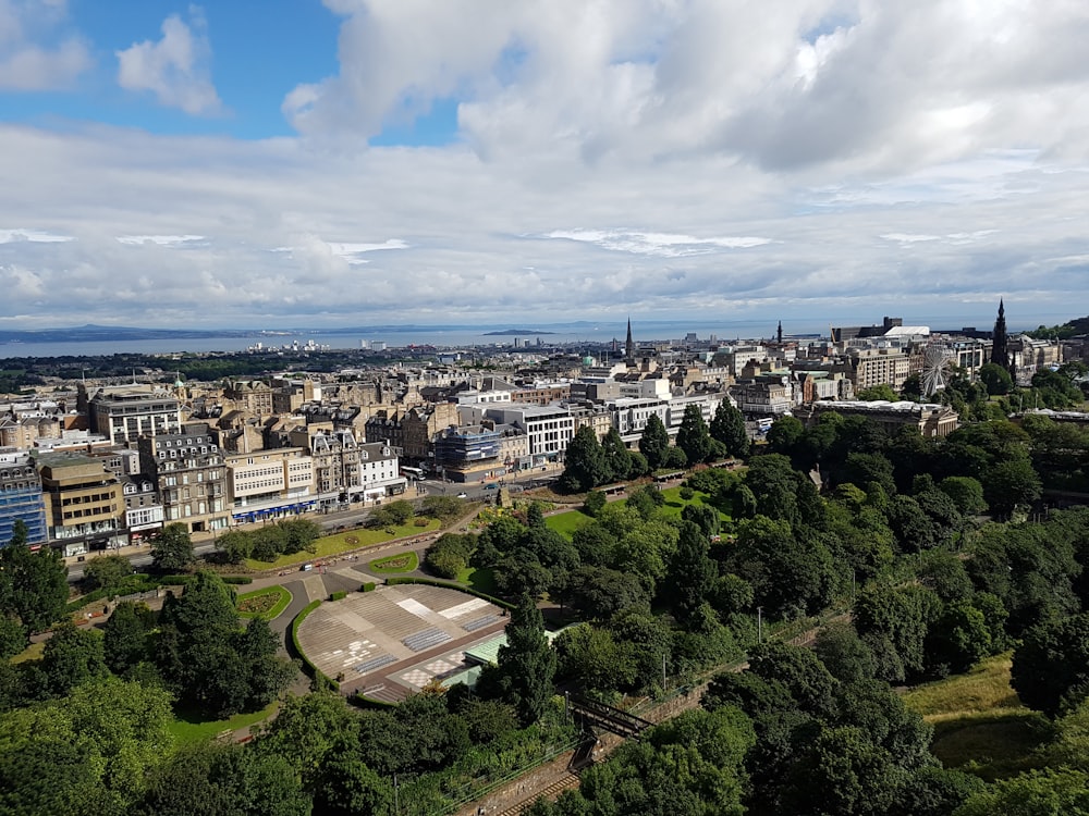 Vue aérienne des bâtiments de la ville et des arbres verts sous un ciel nuageux bleu et blanc pendant la journée