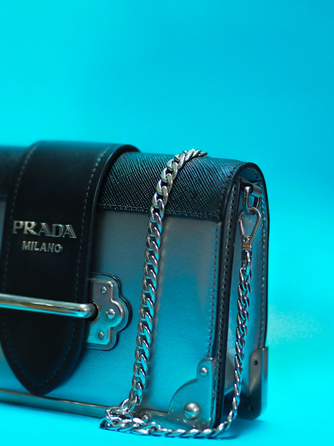 black leather handbag on teal surface