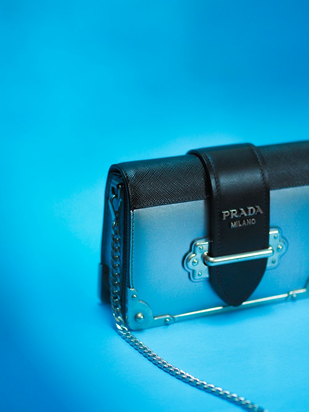 black leather sling bag on blue surface