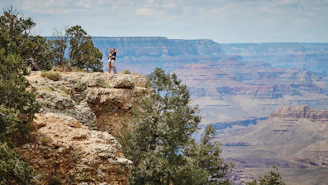 A hiker standing at Artist Point, gazing out over the colorful canyon walls and cascading Lower Falls.