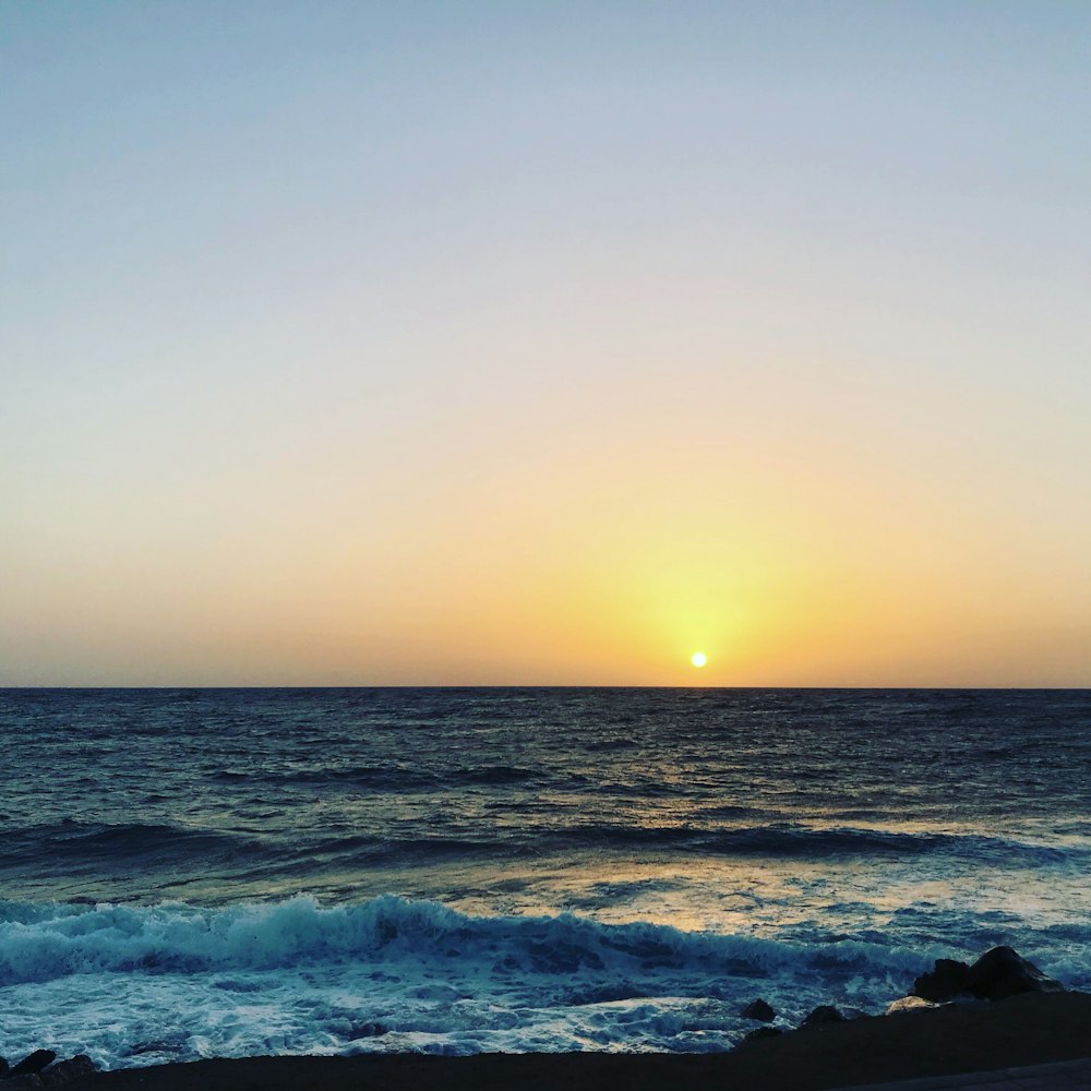 ocean waves crashing on shore during sunset