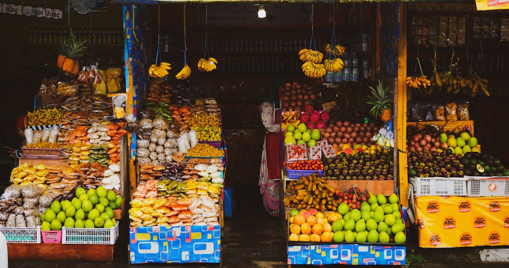 mulher na jaqueta vermelha e branca em pé na frente do estande da fruta