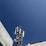 A telecommunications tower equipped with various antennas and equipment surrounded by buildings. The sky is clear and blue, providing a stark, expansive background.