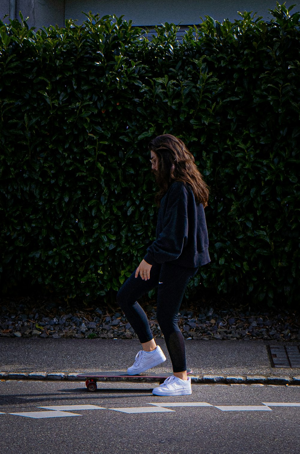 woman in green long sleeve shirt and black pants walking on gray concrete road during daytime
