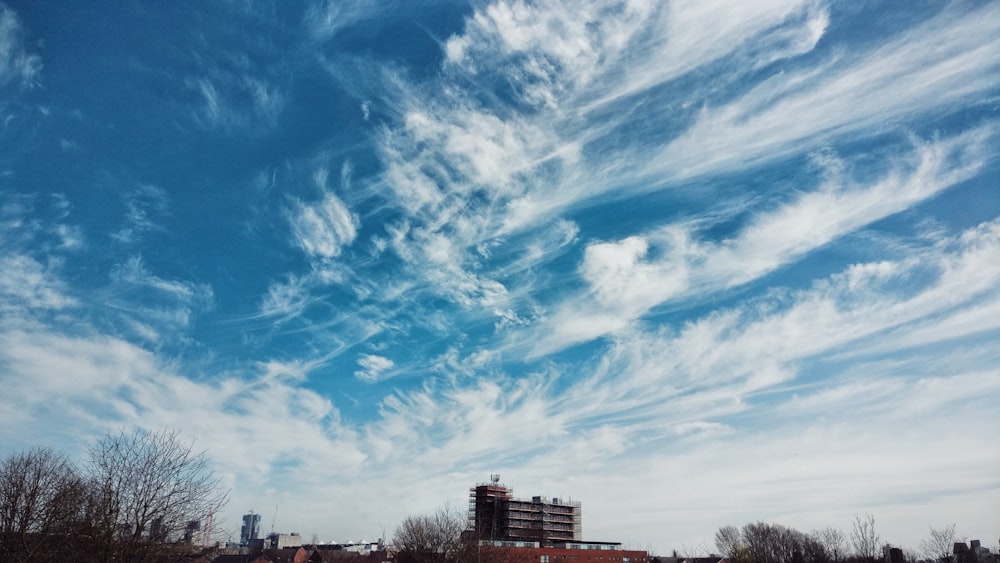 낮에는 푸른 하늘과 흰 구름 아래 갈색 콘크리트 건물