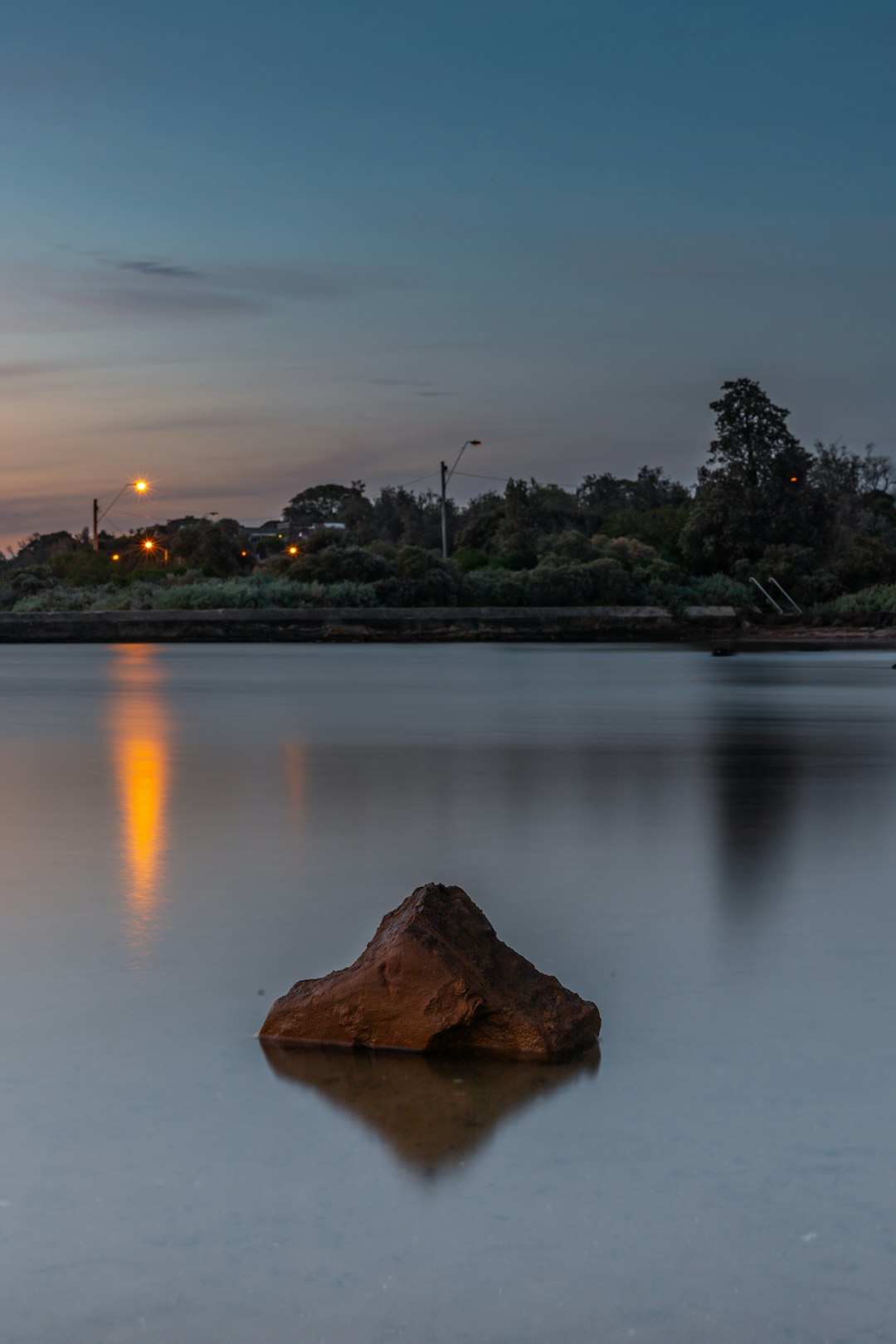 brown rock formation on body of water during sunset