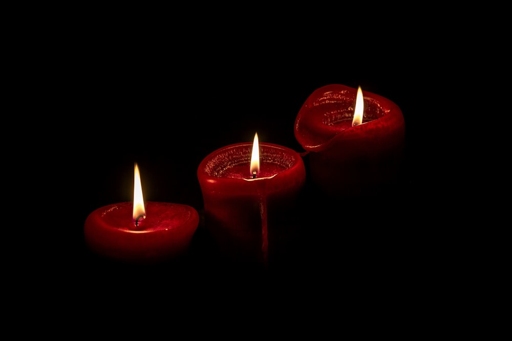 red pillar candles on black surface