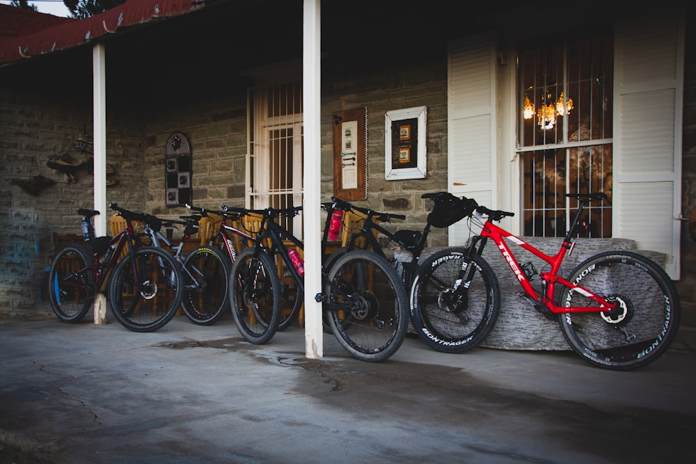 red and black bicycles parked beside brown wooden house during daytime