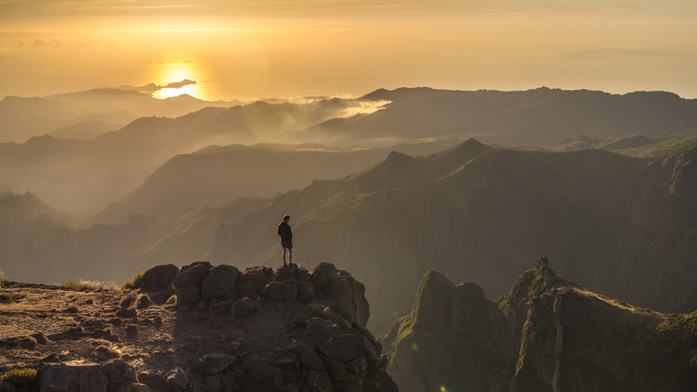 silhouette of person standing on rock formation during daytime