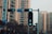 Urban setting with a focus on a traffic light showing green signals for pedestrians and cyclists. High-rise buildings form the backdrop along with some street signs.
