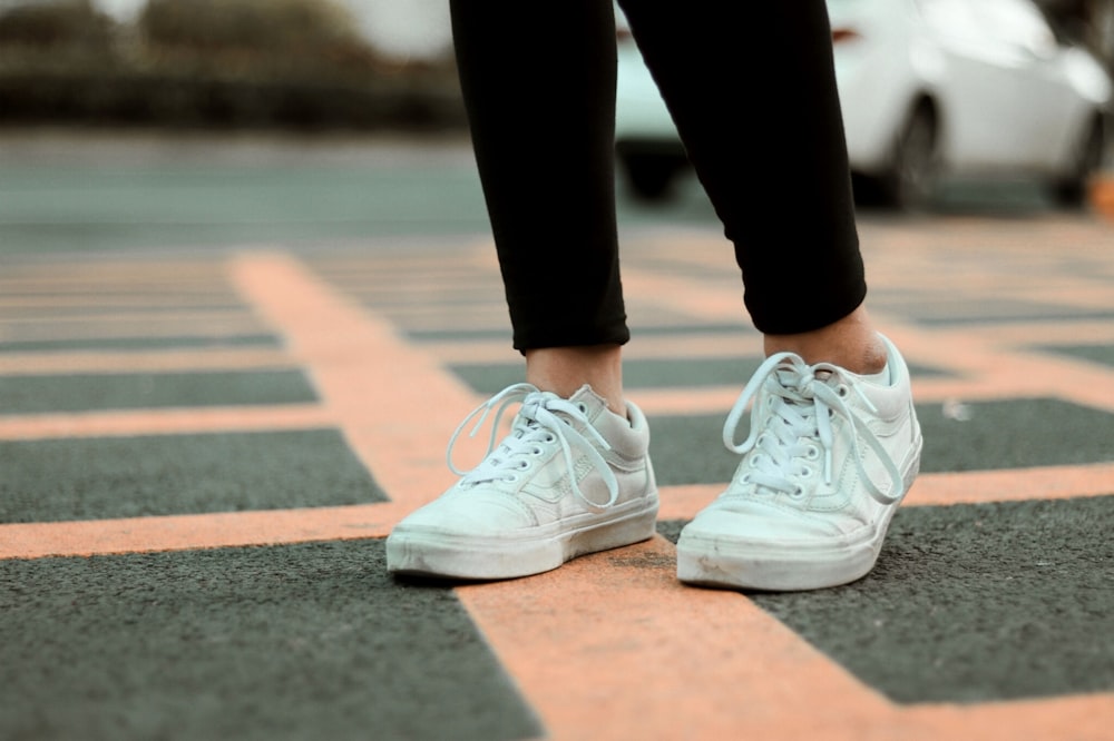 person in black pants and white nike sneakers