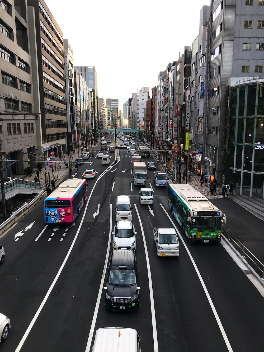 cars on road between high rise buildings during daytime