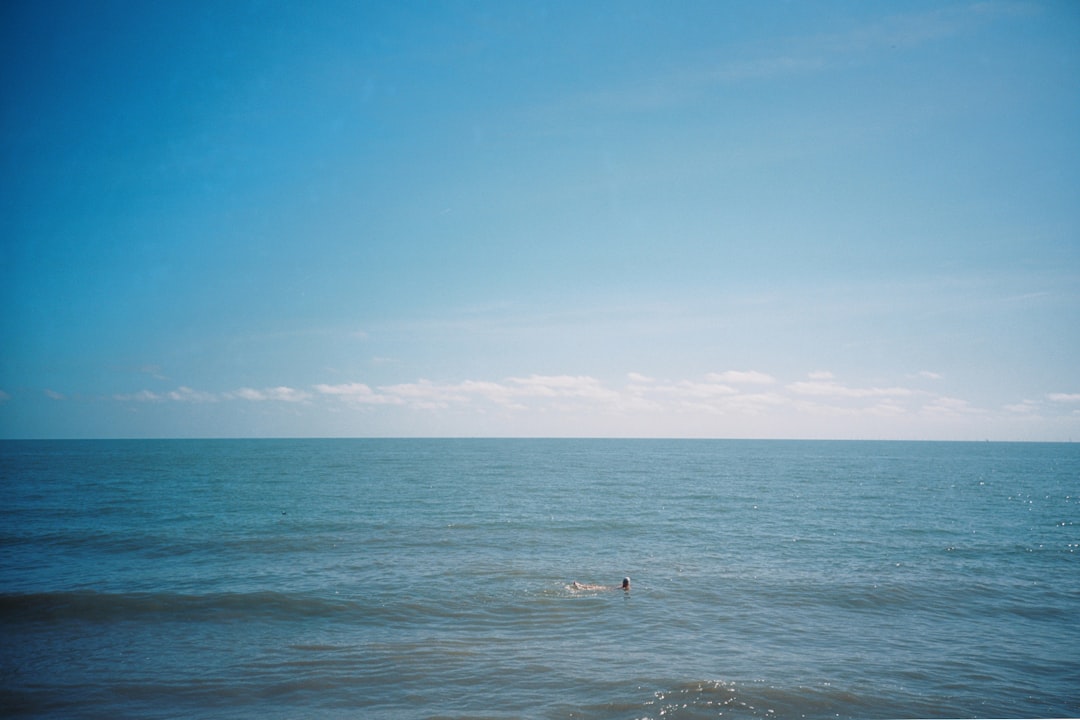 person surfing on sea under blue sky during daytime