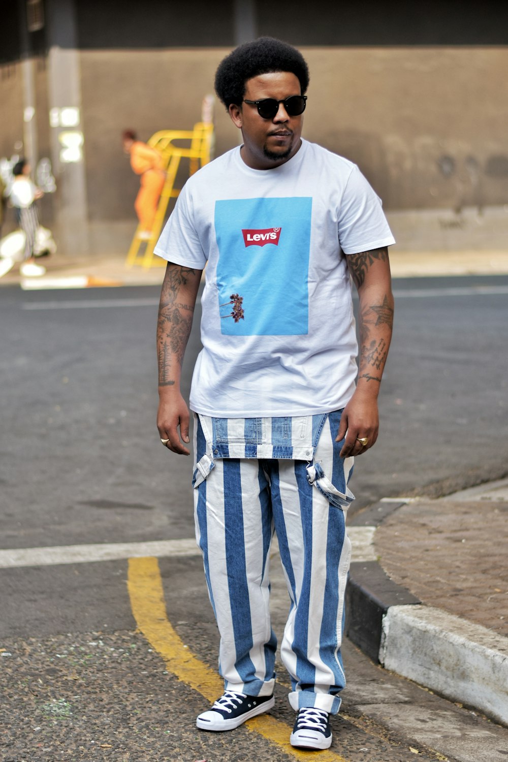 man in white crew neck t-shirt and white and blue pants standing on gray concrete