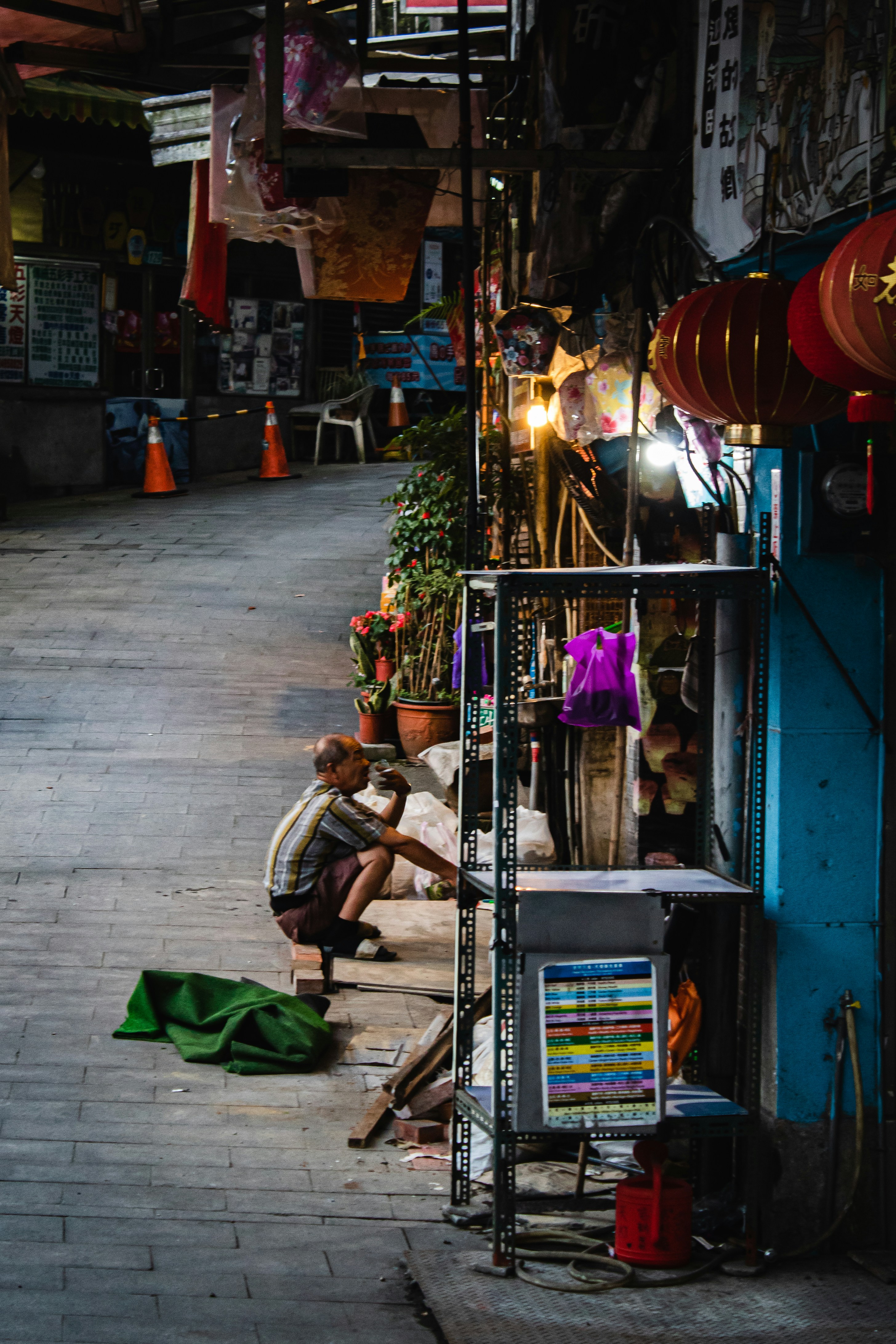 man in white shirt sitting on chair near store during daytime