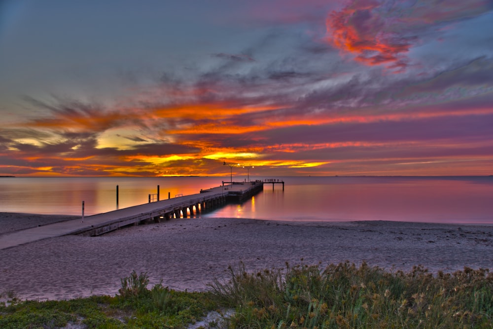 brown wooden dock on sea during sunset