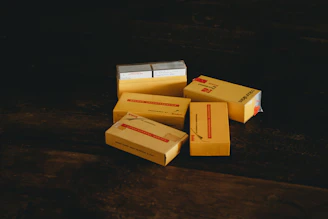 A close-up photo of sealed Pokémon booster boxes stacked neatly on a wooden table.
