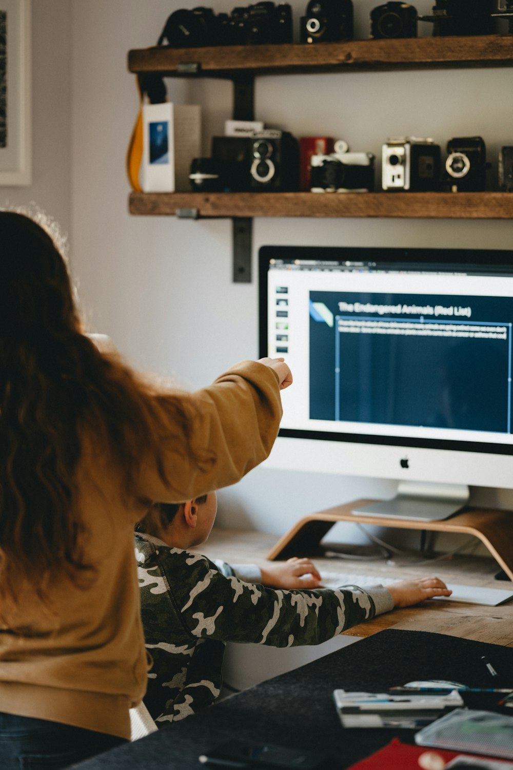 woman in brown long sleeve shirt sitting in front of silver imac