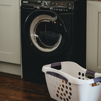 white plastic laundry basket beside black front load washing machine