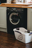white plastic laundry basket beside black front load washing machine