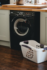 white plastic laundry basket beside black front load washing machine