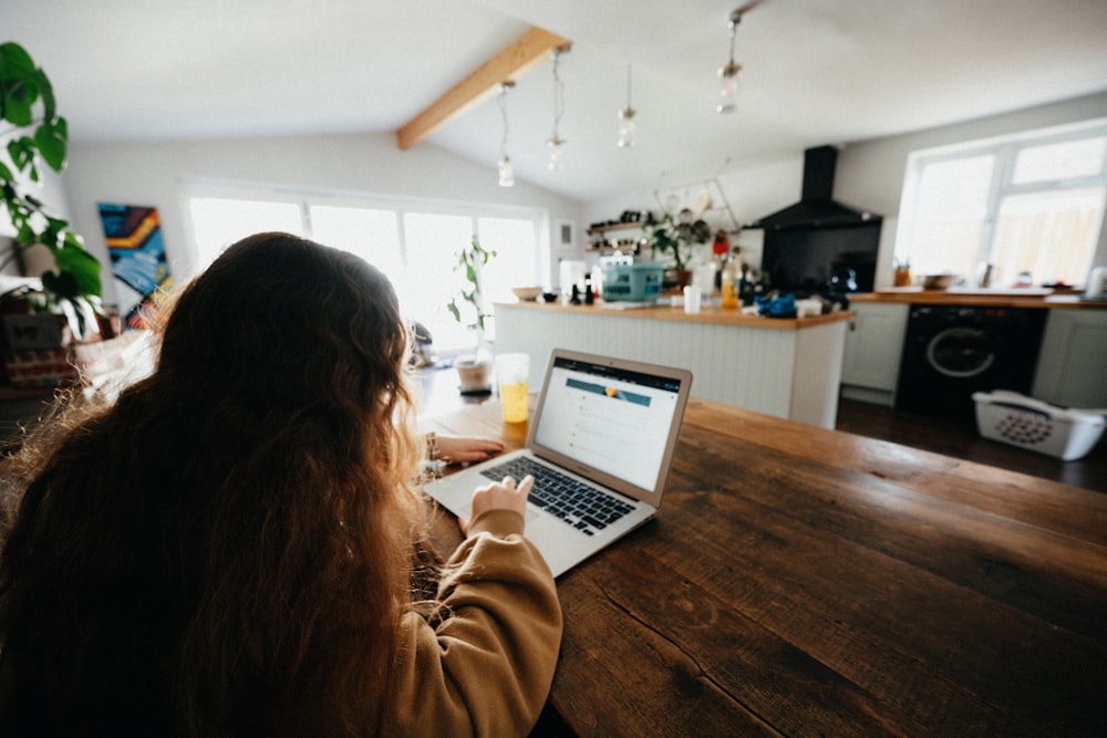 Mujer con suéter marrón usando MacBook Pro