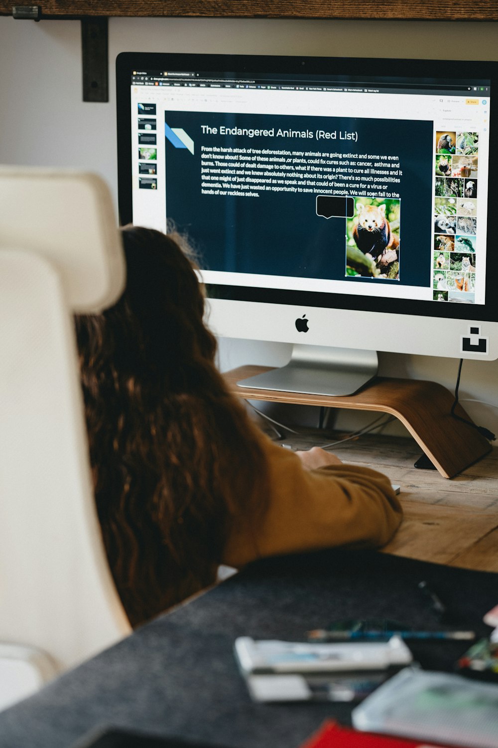 Mujer con camisa negra sentada frente a un imac plateado