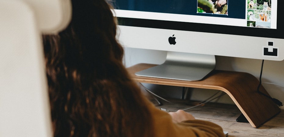 woman in black shirt sitting in front of silver imac