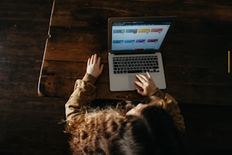 person using macbook pro on brown wooden floor