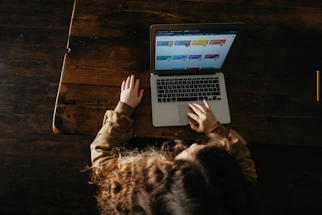 person using macbook pro on brown wooden floor