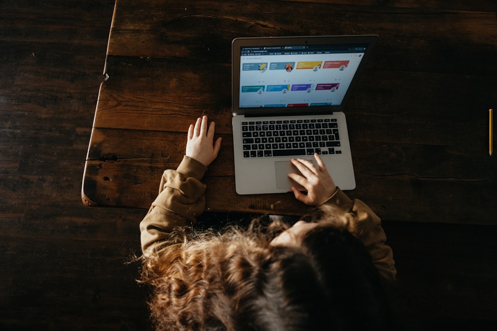 Personne utilisant un MacBook Pro sur un plancher en bois brun